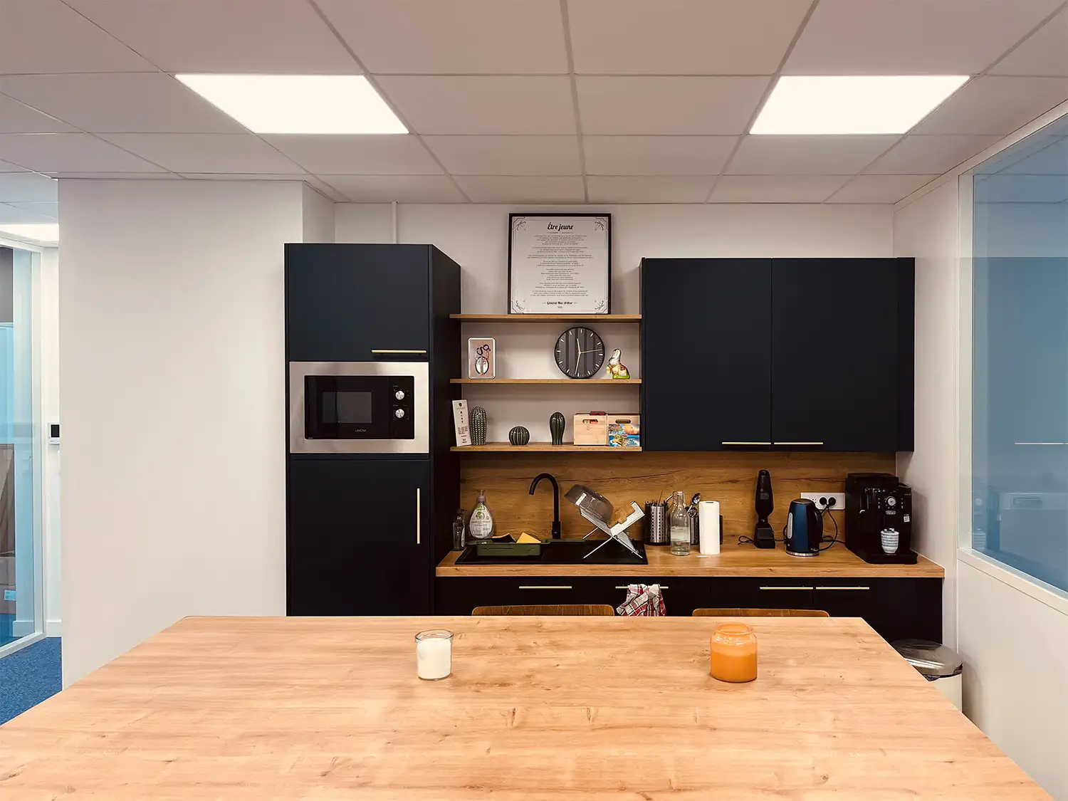 Espace cuisine équipée avec réfrigérateur, micro-ondes, bouilloire et machine à café